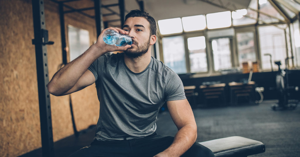 man on bench, drinking water after training